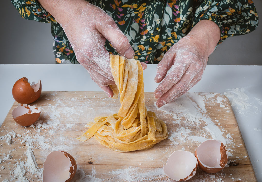 An Image of a woman's hands and her freshly made pasta noodles